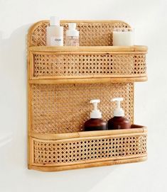 two bamboo shelves with soap and lotion bottles on them, against a white wall