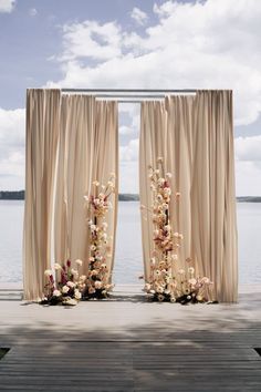 an outdoor ceremony setup with flowers and draping on the front door, overlooking water