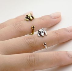 a person's hand with three rings on it, one has a dog and the other has a cat