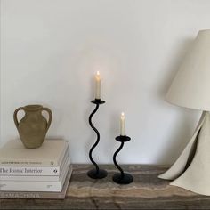 two black candles are next to each other on a table with books and a vase