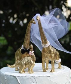 two gold giraffe figurines on top of a white cake