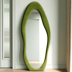 an oval shaped mirror sitting on top of a wooden floor next to a white door