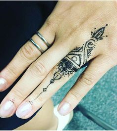 a woman's hand with a black and white tattoo design on the middle finger