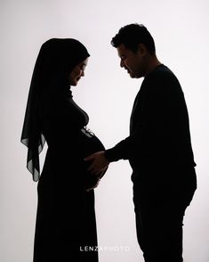 a man and woman standing next to each other with their hands on their bellys