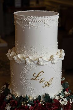 a three tiered white wedding cake with red flowers