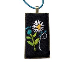 a necklace with a flower on it and beads around the edges, hanging from a cord