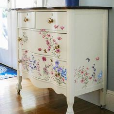 a white dresser with flowers painted on it