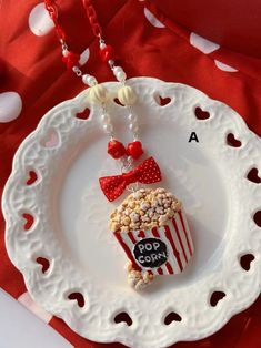 a white plate topped with a red and white cup filled with popcorn on top of it