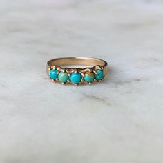 View in 14K Gold. Five 3-millimeter turquoise stones are hand-set in this simple and delicate ring. Click [here] to learn more about this stunning, meaningful gemstone. Not sure about your ring size? Order a ring sizer here! *Note: Photo of loose turquoise stones displays the color variations for this particular piece. You may receive a mix of these colors or all of one color depending on our stock. At this time, we are not able to take special requests for stone color preferences and do no acce Dainty 14k Gold Turquoise Ring, Dainty 14k Gold Turquoise Gemstone Ring, Dainty Turquoise Ring For Anniversary, Turquoise Yellow Gold Promise Ring, 14k Gold Turquoise Promise Ring, 14k Yellow Gold Turquoise Promise Ring, Heirloom Turquoise Ring In 14k Gold For Anniversary, Yellow Gold Turquoise Promise Ring, Cake Pull Charms