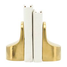 Add a contemporary touch to your bookcase with these Gold Ceramic Curved Bookends! Their chic gold finish and eye-catching curved design will bring a sleek flair to your book collection! Bookends measure 4L x 6W x 6H in. Crafted of ceramic Gold finish Feature a curved design Weight: 2.16 lbs. Care: Dust with a soft, dry cloth. This item is available at Kirklands.com only, not available in stores. Please note: this item cannot be shipped to APO/FPO addresses. | Ceramic Curved Bookends, Gold, 4L x 6W 6H | Kirkland's Home Bookends Gold, Gold Office, Gold Book, Gold Ceramic, Bookshelf Decor, Shelf Decor, Book Collection, Gold Finish, Bookends