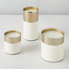 three white and gold candle holders sitting on a table