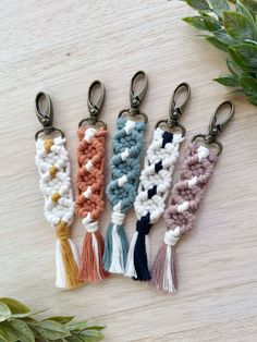 four crocheted key chains with tassels on top of a wooden table