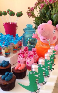 a table topped with cupcakes and cakes covered in fondant peppa the pig