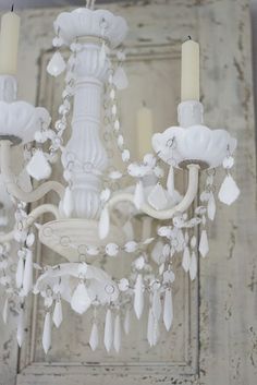 a white chandelier hanging from the ceiling with two candles in front of it