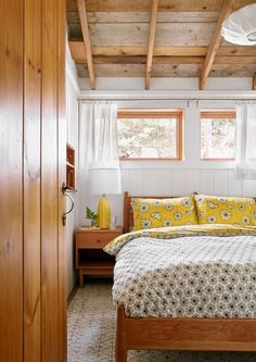 a bed with yellow and white comforter in a bedroom next to a wooden door