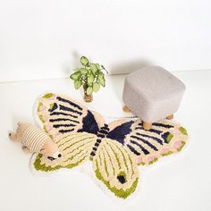 a rug with a butterfly on it next to a potted plant and a stuffed animal