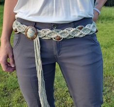 a person wearing a white shirt and gray pants with a braided belt around their waist