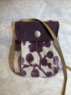 "What makes this adorable little purse perfect? The purse body features a purple plush and linen tapestry weave with a dark plum textured flap.  For a little bag, the purse has so much room! It's organized with a main inner pouch, a back pouch (for easy access to phone) and 2 outer front pouches. You wouldn't believe how much fits inside! It closes with a  magnetic snap so everything stays inside.  Measurements: 9\" widest x 9.5\" high Strap: 48\" long Constructed with designer upholstery weight Modern Square Bag With Cell Phone Pocket, Daily Use Purple Crossbody Phone Bag, Versatile Crossbody Pouch With Zipper Pocket, Versatile Rectangular Satchel With Cell Phone Pocket, Modern Red Bag With Cell Phone Pocket, Burgundy Travel Bag With Cell Phone Pocket, Purple Travel Phone Bag With Removable Pouch, Burgundy Crossbody Shoulder Bag With Cell Phone Pocket, Burgundy Crossbody Bag With Cell Phone Pocket