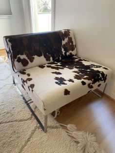 a cow print couch sitting on top of a hard wood floor next to a window