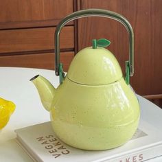 a yellow tea pot sitting on top of a book