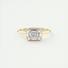 an emerald - cut diamond ring in yellow gold, set with a baguette