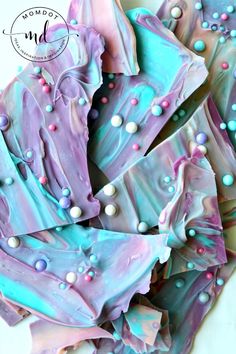 purple and blue decorated cookies are on a plate with white frosting, sprinkles, and beads