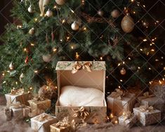 a christmas tree with presents under it and an open gift box in front of it