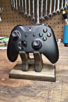 a close up of a game controller on a wooden stand with tools in the background