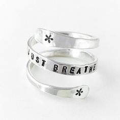 This ring is so comfortable to wear! Created from sterling silver wire, this ring is hand-flattened and hand-stamped with the words JUST BREATHE and some wispy swirls on either side, and gently wraps around your finger as a constant reminder to exhale. This ring can be personalized with Inspirational Adjustable Sterling Silver Rings, Adjustable Inspirational Sterling Silver Rings, Inspirational Adjustable Silver Rings, Adjustable Spiritual Sterling Silver Engraved Ring, Meaningful Adjustable Silver Stackable Rings, Adjustable Sterling Silver Engraved Ring, Nickel Free, Adjustable Sterling Silver Stackable Rings, Adjustable Nickel Free Sterling Silver Engraved Ring, Adjustable Nickel-free Sterling Silver Engraved Ring