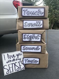 three cardboard boxes stacked on top of each other in front of a car with stickers that say, touch smell sight sound taste