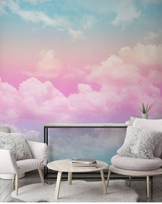 two chairs and a coffee table in front of a wall with clouds painted on it