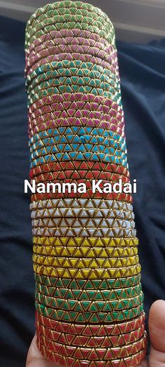 a hand holding a stack of multicolored bracelets with the words namma kadai written on it