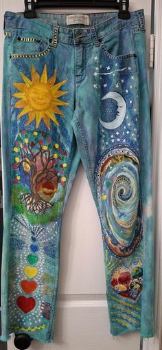 a pair of blue jeans with an image of the sun and moon painted on them