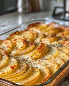 a casserole dish with potatoes and cheese in a glass baking dish on a counter