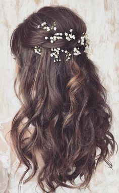 the back of a woman's head with long hair and flowers in her hair