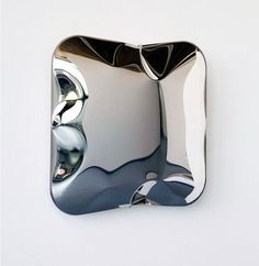 a shiny metal object on a white wall