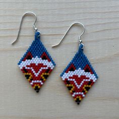 These earrings feature the iconic mask of San from Studio Ghibli's Princess Mononoke. A deep blue background brings to mind a dark forest at night. They are lovingly beaded using high-quality Miyuki Delica 11/0 beads and finished with a .925 sterling silver hook. Enchanting and fierce! Princess Mononoke Cross Stitch, Princess Mononoke Mask, Mononoke Mask, Stitch Earrings, Princess Mononoke, Loom Weaving, Dark Forest, Jewellery Making, Studio Ghibli