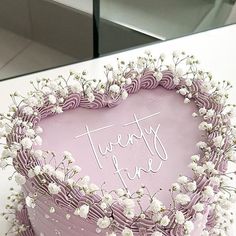 there is a heart shaped cake with white flowers on the top and writing that reads twenty five