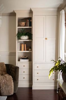 a living room filled with furniture and lots of white cupboards next to a window