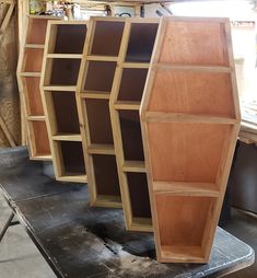 three wooden bookshelves sitting on top of a piece of plywood in a workshop