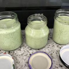 three jars filled with green liquid sitting on top of a counter