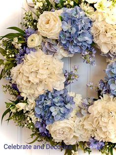 a wreath with blue and white flowers hanging on the front door to celebrate and decorate