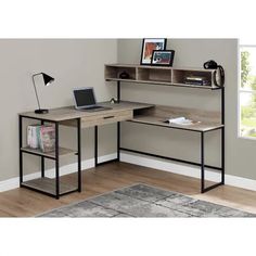 a computer desk with a laptop on top of it in front of a gray wall