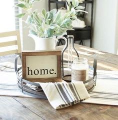 a wooden table topped with a vase filled with flowers next to a sign that says home