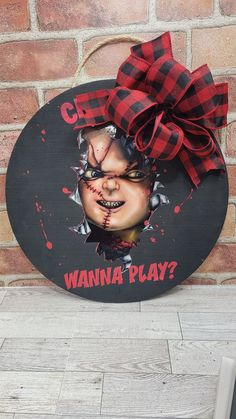 a wooden sign with the words wanna play painted on it and a red bow hanging from it's side