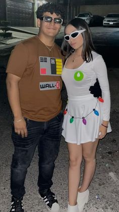 a man standing next to a woman in a white dress and black shoes, both wearing sunglasses