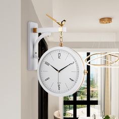 a white clock hanging from the side of a wall next to a dining room table