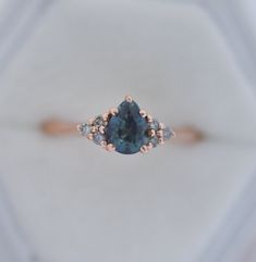 an engagement ring with a blue diamond surrounded by three smaller diamonds on the top and bottom