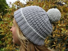 a woman wearing a knitted hat with two pom - poms on it