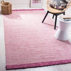 a pink rug with fringes on the floor in a white room next to a chair